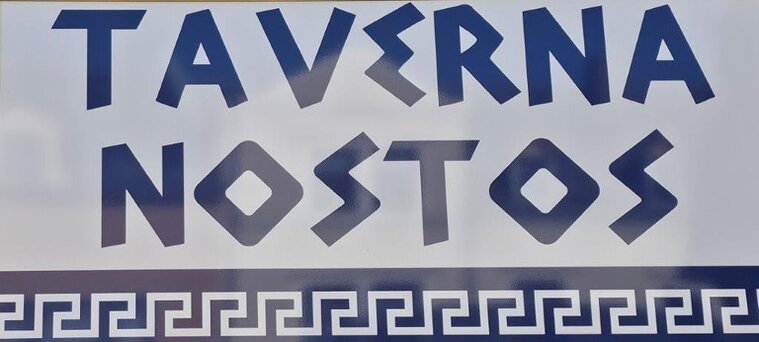 Biergarten der Taverne Nostos mit Gästen an Holztischen